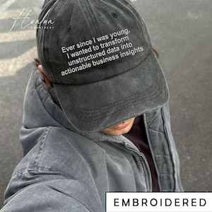 May include: A dark grey baseball cap with the text "Ever since I was young, I wanted to transform unstructured data into actionable business insights." The word "EMBROIDERED" is at the bottom.