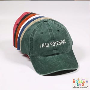 Pode incluir: Uma caneca de cerâmica branca com uma alça preta e o texto "But First, Coffee" em negrito preto. A caneca está sobre um fundo desfocado, sugerindo um ambiente acolhedor.