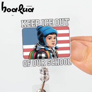 May include: A white badge reel with a rectangular design featuring a child wearing a blue hat and backpack in front of an American flag. The text reads "KEEP ICE OUT OF OUR SCHOOL".