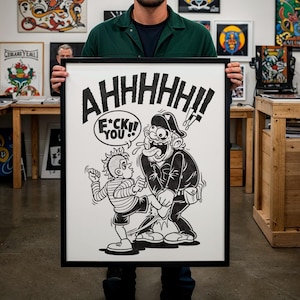 Puede incluir: Una impresión de dibujos animados en blanco y negro enmarcada con las palabras "AHHHHH!!" y "F*CK YOU!!" mostradas de forma destacada. La obra de arte representa dos personajes de dibujos animados en una pose de confrontación. La impresión la sostiene una persona con una camisa verde.