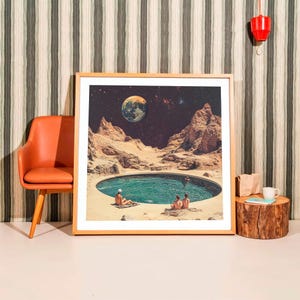 Könnte beinhalten: Ein gerahmter Kunstdruck zeigt eine surreale Landschaft mit einem Pool und Figuren, vor dem Hintergrund eines Planeten und eines Sternenhimmels. Das Kunstwerk befindet sich in einem hellen Holzrahmen. Ein orangefarbener Stuhl und ein Beistelltisch aus Holz sind im Hintergrund.
