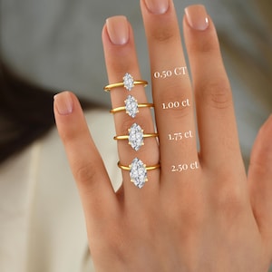 May include: Four gold rings with marquise-cut stones in varying sizes, labeled 0.50 CT, 1.00 ct, 1.75 ct, and 2.50 ct. Each ring features a single clear stone set on a thin yellow gold band, displayed in a vertical arrangement on a finger.