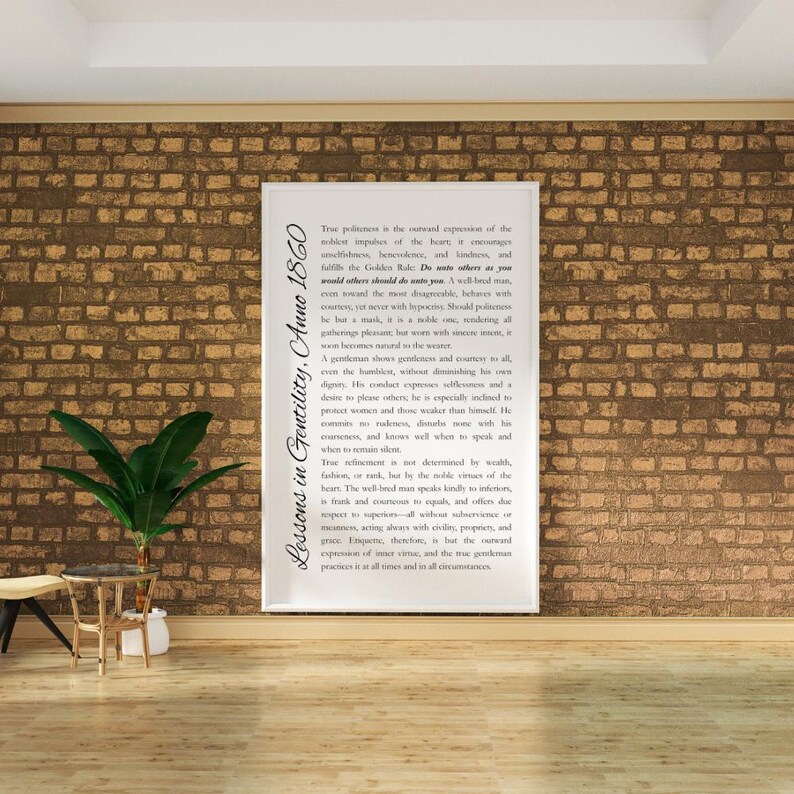 May include: A framed print with the text "Lessons in Gentility, Anno 1860" against a brick wall. The print features a lengthy passage of text in a serif font. A small potted plant and side table are in the foreground.