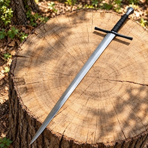 Puede incluir: Una espada de acero de doble filo con punta afilada, una guarda recta y un mango negro acanalado rematado con un pomo metálico. La hoja tiene una superficie pulida y reflectante que se estrecha hacia el extremo puntiagudo y afilado.