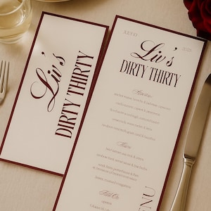 Könnte beinhalten: Zwei Menüs mit weinroten Rändern und Text, die "Liv's Dirty Thirty" und ein Datum anzeigen. Die Speisekarte listet Vorspeisen, Hauptgerichte und einen Abschnitt "Full On" auf. Ein Weinglas, eine Gabel und ein Messer sind sichtbar.