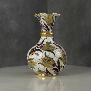 May include: A white ceramic mug with a black handle and the text "But First, Coffee" in a black, handwritten-style font. The mug is on a white surface.