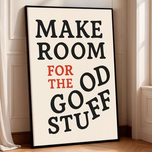 Può includere: Un poster incorniciato con le parole "MAKE ROOM FOR THE GOOD STUFF" in testo nero e rosso. Il poster ha uno sfondo color crema e una cornice nera. Il poster è appoggiato a un muro.