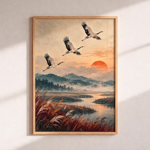 Peut inclure: Une impression d'art encadrée représentant trois grues blanches et noires volant au-dessus d'un paysage fluvial brumeux au coucher du soleil. La scène présente de grands roseaux bruns au premier plan, des montagnes et un grand soleil orange.