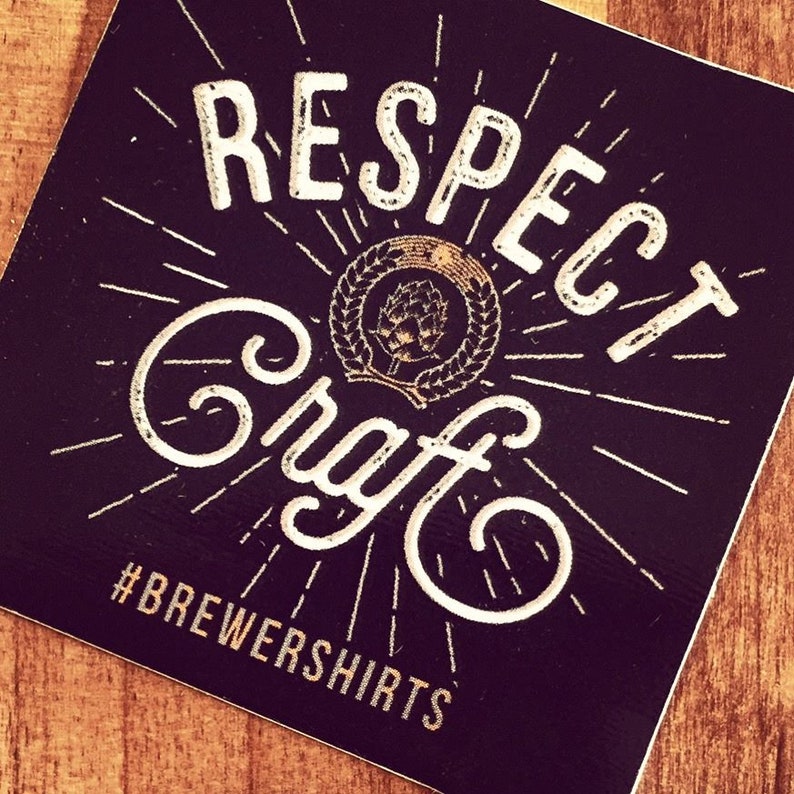 Puede incluir: Adhesivo cuadrado negro con texto blanco que dice "RESPECT Craft" en una fuente estilizada. Un emblema circular con un dise&ntilde;o de l&uacute;pulo est&aacute; en el centro. El texto "#BREWERSHIRTS" est&aacute; en la parte inferior, con l&iacute;neas radiales.