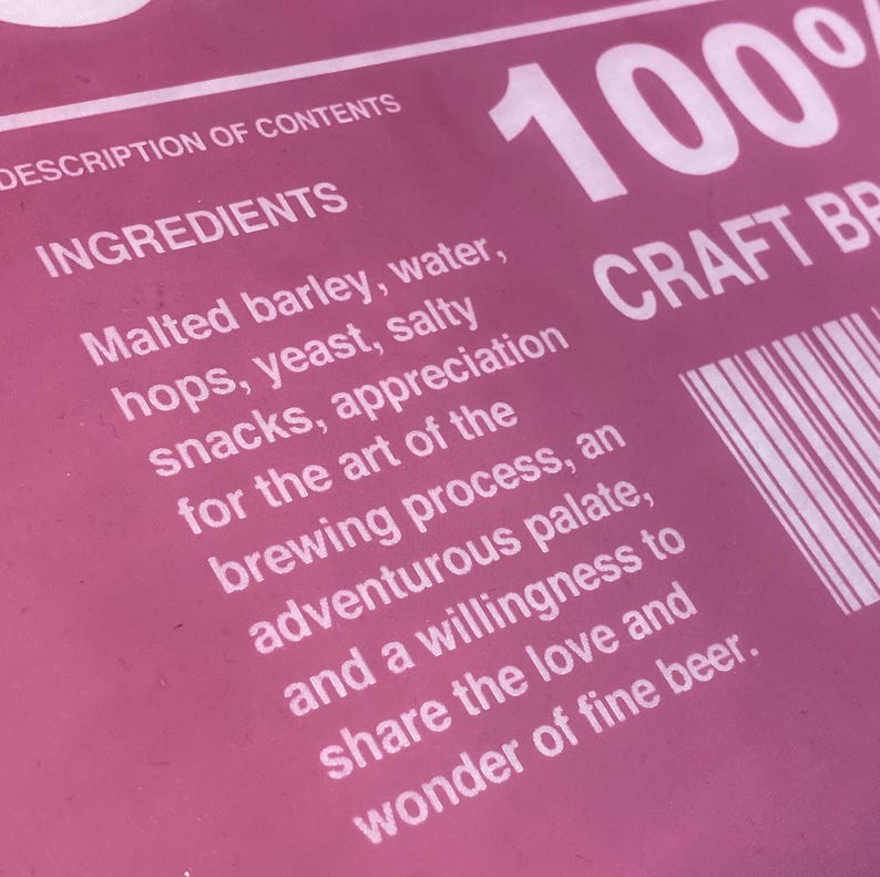 Puede incluir: Una etiqueta rosa con texto blanco que describe los ingredientes de una cerveza artesanal. El texto dice "DESCRIPTION OF CONTENTS INGREDIENTS Malted barley, water, hops, yeast, salty snacks, appreciation for the art of the brewing process, an adventurous palate, and a willingness to share the love and wonder of fine beer." La etiqueta tambi&eacute;n incluye el texto "100% CRAFT BEER".