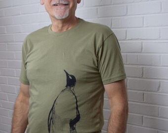 May include: A man wearing a green t-shirt with a black and white penguin graphic print.