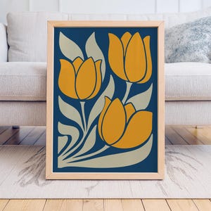 Könnte beinhalten: Gerahmter Kunstdruck mit stilisiertem Blumendesign. Das Kunstwerk zeigt drei große orangefarbene Tulpen mit graugrünen Blättern vor einem tiefblauen Hintergrund. Der Druck ist in einem hellen Holzrahmen, geeignet für die Inneneinrichtung.