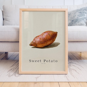 Puede incluir: Una impresión enmarcada que presenta una ilustración realista de una batata. La obra de arte muestra el tubérculo en tonos naranja y morado sobre un fondo neutro. Las palabras "Sweet Potato" están impresas debajo.