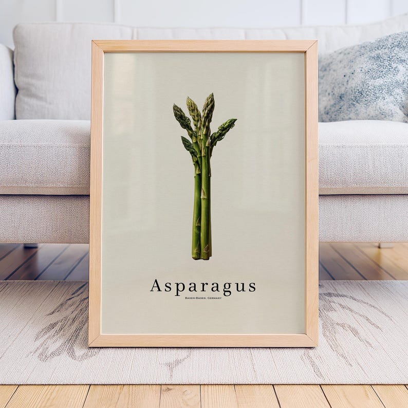 May include: A framed print featuring a botanical illustration of asparagus. The artwork showcases a bundle of green asparagus spears against a light beige background. The word "Asparagus" is printed in a simple font below the image.