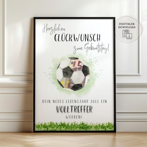 May include: A framed print featuring a soccer ball design with a watercolor effect. The soccer ball incorporates elements of currency. The print includes German text wishing a happy birthday and a message about a successful new year.