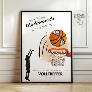 Könnte beinhalten: Ein gerahmter Druck mit Basketball-Motiv. Das Bild zeigt einen Basketball in der Luft, der auf einen Korb zugeht, mit der Silhouette einer Person, die den Ball wirft. Der Text auf Deutsch lautet "Herzlichen Glückwunsch zum Geburtstag!" und "Dein neues Lebensjahr soll ein Volltreffer werden!"