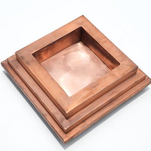 Può includere: Un vassoio decorativo quadrato color rame con un design a più livelli. Il vassoio ha un centro incassato e un bordo rialzato e incorniciato. La finitura ramata conferisce al vassoio un aspetto metallico caldo. Il vassoio è adatto per contenere piccoli oggetti.