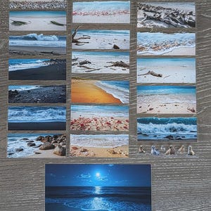 May include: A collection of rectangular stickers featuring various beach scenes, including ocean waves, sandy shores, driftwood, rocks, and a night seascape with a full moon. The stickers display diverse coastal landscapes with blue water and natural elements.