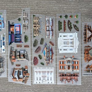 Könnte beinhalten: Transparenter Aufkleberbogen mit Illustrationen von Häusern und Landschaftselementen. Der Bogen enthält moderne und traditionelle Hausdesigns, Bäume und Sträucher. Auf dem Bogen steht "Houses 1.0" und "Loopology by Laurie".