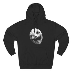 May include: Black hooded sweatshirt featuring a white, detailed illustration of a smiling face. The design is centered on the front of the sweatshirt, with a kangaroo pocket and drawstring hood. The sweatshirt is made of a soft material.