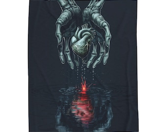 May include: A dark blanket featuring a detailed illustration. Two skeletal hands cradle a human heart, positioned above rippling water. A red light emanates from the water's surface, creating a reflection of the heart. The artwork is rendered in shades of gray and black.