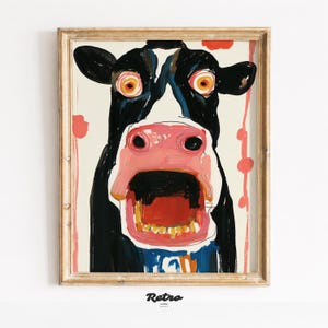 Può includere: Una stampa artistica incorniciata con un ritratto di mucca colorato ed espressivo. La mucca ha una faccia in bianco e nero con grandi occhi arancioni e una bocca spalancata. L'opera è incorniciata in una cornice dorata, con la parola "Retro" in basso.
