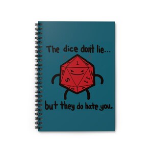 May include: Spiral-bound notebook with a teal cover featuring a cartoon d20 die with arms and legs. The text reads "The dice don't lie... but they do hate you."