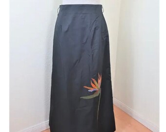 May include: A black skirt with a bird of paradise design on the side. The skirt is made of a silky fabric and has a simple, elegant style.