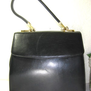 May include: A black leather handbag with a gold-toned handle and clasp.