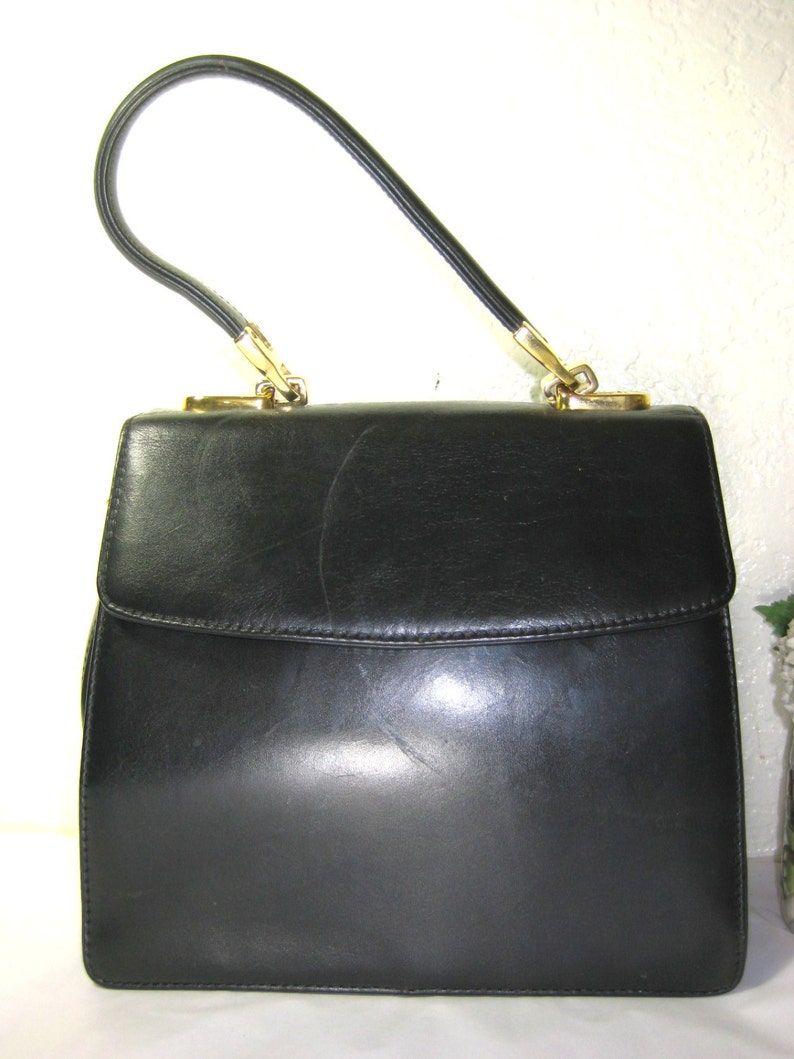 May include: A black leather handbag with a gold-toned handle and clasp.