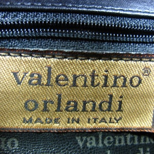 May include: A brown leather purse with a gold label that reads "valentino orlandi made in italy".