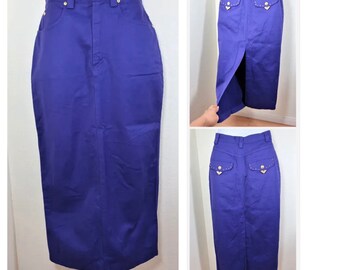 May include: A long, purple denim skirt with a back slit and gold accents on the back pockets.