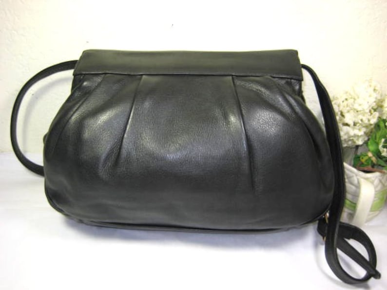 May include: A black leather handbag with a pleated design and a long strap.