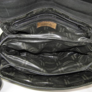 May include: Black leather handbag with multiple compartments and a zipper closure. The bag has the text "Valentino Orlandi" printed on the inside.