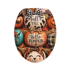 Op de afbeelding: Een ovale toiletbrilhoes met een decoratieve herfstscène met meerdere pompoenen. De pompoenen zijn versierd met strikken, patronen en teksten waaronder Fall Y'ALL en Hello PUMPKIN. Het ontwerp bevat oranje, witte en blauwgroene kleuren.