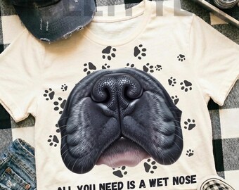 May include: Cream-colored crop top featuring a large, detailed illustration of a black dog nose. The shirt is adorned with paw prints and the text "ALL YOU NEED IS A WET NOSE".