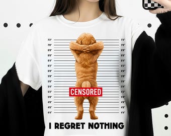 May include: White crew neck t-shirt featuring a cartoon dog with its paws crossed behind its head, mimicking a mugshot. The word "CENSORED" is in a red rectangle, and the text "I REGRET NOTHING" is below the dog. Height markings are on the sides.