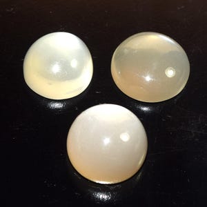 Könnte beinhalten: Ein Set aus drei Keramikbechern mit gesprenkelter, matter Oberfläche. Die Becher sind in Creme-, Hellgrau- und Dunkelgrautönen gehalten. Jeder Becher hat ein schlichtes, minimalistisches Design.