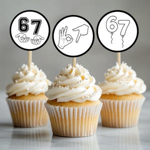 Puede incluir: Tres cupcakes con glaseado blanco y chispas plateadas. Cada cupcake tiene una cobertura circular con el número 67 en diferentes diseños: uno con manos, uno con gestos con las manos y otro con números en forma de globo.