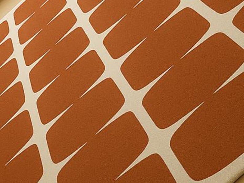 May include: Close-up of a patterned textile. It features a repeating design of rust-coloured rectangular shapes with white, pointed accents. The shapes are arranged in a grid-like pattern, creating a textured visual effect.