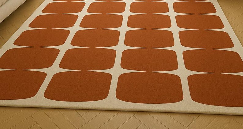 May include: A rectangular rug featuring a repeating pattern of rust-coloured, rounded rectangles on a cream background. The rug is made of a soft material, suitable for a living room or bedroom.