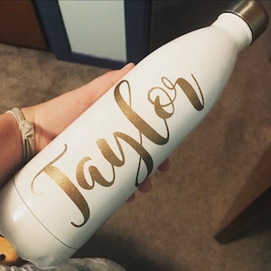 May include: White water bottle with a gold glitter name "Taylor" on the side.