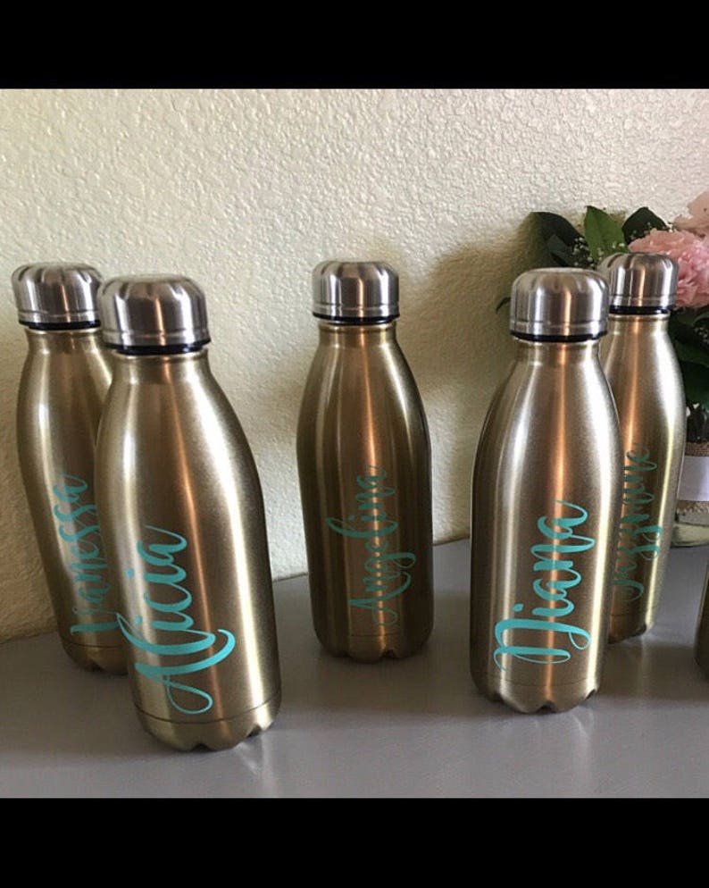 May include: Five gold-colored water bottles with personalized names in teal lettering. The names are "Melissa", "Alicia", "Angelina", "Diana", and "Jasmine".