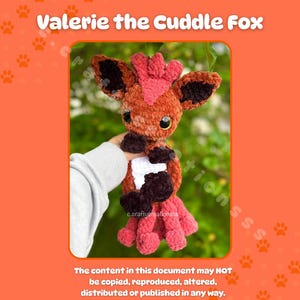Op de afbeelding: Een handgemaakte gehaakte vos genaamd Valerie, met een bruin-roze kleurenschema. De vos heeft grote ogen, een pluizige manen en een uniek ontwerp. De afbeelding bevat de tekst "Valerie the Cuddle Fox".