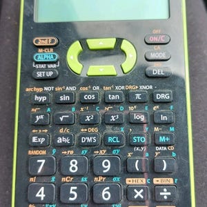 Könnte beinhalten: Ein schwarzer und grüner wissenschaftlicher Taschenrechner Sharp EL-531X mit zahlreichen Tasten für mathematische Funktionen. Der Rechner hat einen grünen Rand und ein Display. Der Text "SHARP ADVANCED D.A.L." ist sichtbar.