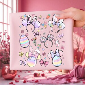 May include: A pink fabric featuring Easter-themed illustrations. Designs include bunny ear headbands, Easter eggs, bows, flowers, and a small bunny character. The artwork is in pastel colors with a whimsical style.