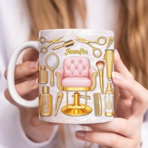 Puede incluir: Taza de cerámica blanca con una silla de barbero rosa y dorada, tijeras doradas y otras herramientas de salón. El nombre "Jennifer" está escrito en letras doradas. La taza tiene un asa blanca y un fondo marmolado.