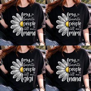 May include: Black t-shirts with a daisy graphic and text. The shirts say "my favorite people call me mama", "mimi", "gigi", and "nana". The daisy has a yellow center and white petals.