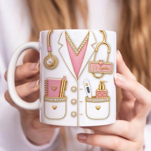 Puede incluir: Taza de cerámica blanca con diseño de bata de médico, detalles dorados y cuello rosa. La taza incluye un estetoscopio, bloc de notas, bolígrafo, termómetro y dispensador de jabón. El nombre "Dr. Sophia" está en una etiqueta.