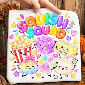 May include: A white t-shirt featuring the colourful text SQUISH SQUAD above cartoon illustrations of a popcorn bucket, a purple cube, a stick of butter, a rainbow dumpling, a paw print, and a white dumpling, all with smiling faces.